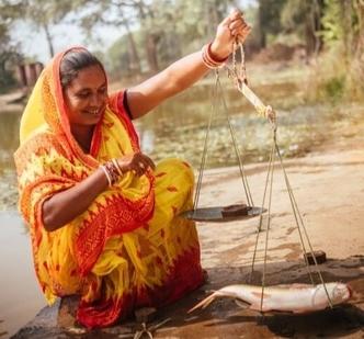 Indian women holding a fish on scale